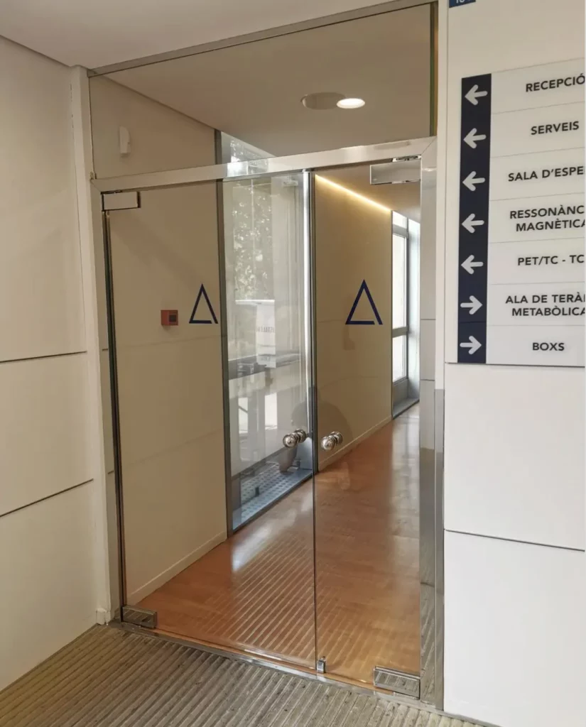Puerta de vidrio templado con herrajes inox en pasillo de centro sanitario