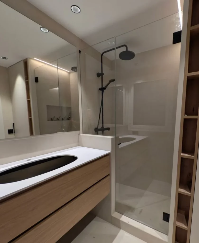 Mampara batiente fija con perfilería negra en baño moderno