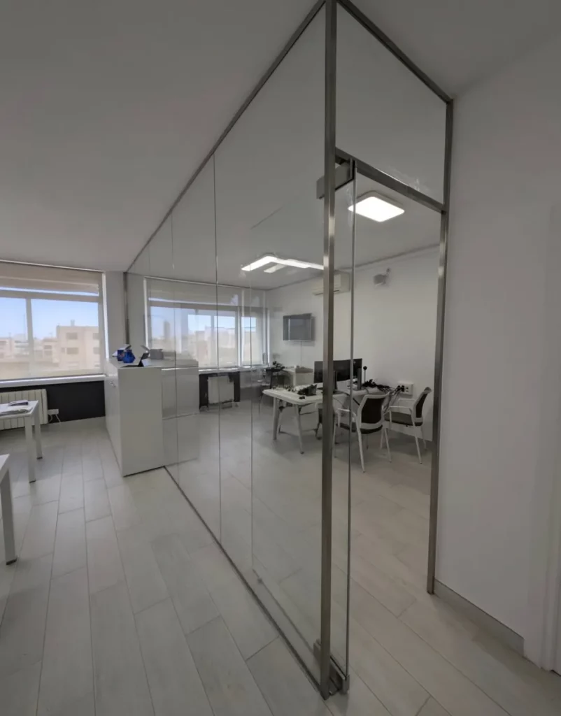 Tabique de vidrio a toda altura con puerta integrada en oficina moderna